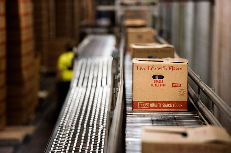 Boxes of Herr's snacks on a conveyor belt ready to be shipped